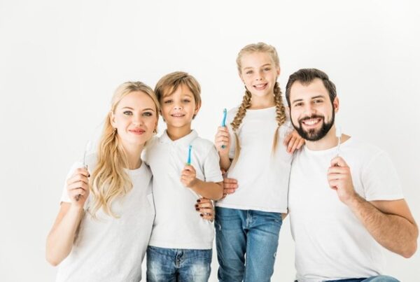 portrait of family of four holding toothbrushes